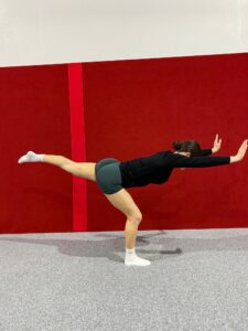 Gymnast in a balancing position with arms extended and one leg lifted